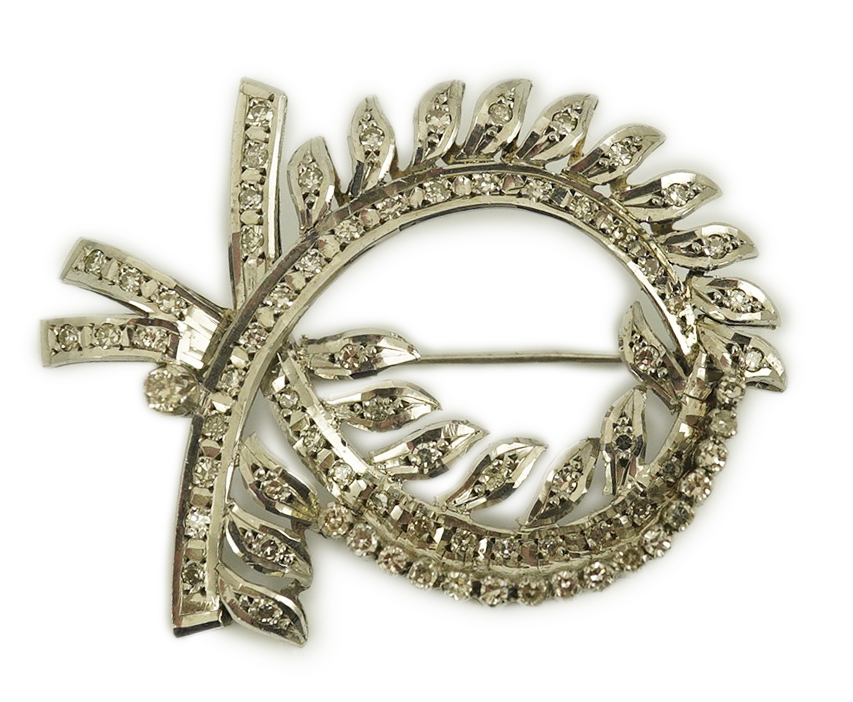 A recent white gold and diamond cluster set scrolling wreath brooch